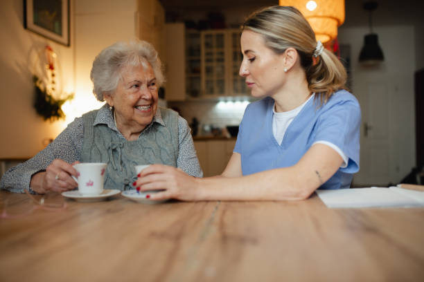 istock Lovely eldery woman serving tea to friendly caregiver during home visit. 2199605969