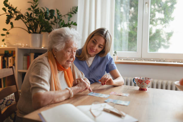 istock Social worker helping elderly lady with managing her finances, counting banknotes. 2199606130