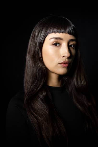 istock Confident young woman staring at camera against black background 2199609355