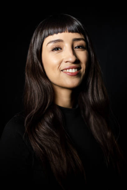istock Happy young woman smiling at camera against black background 2199609356