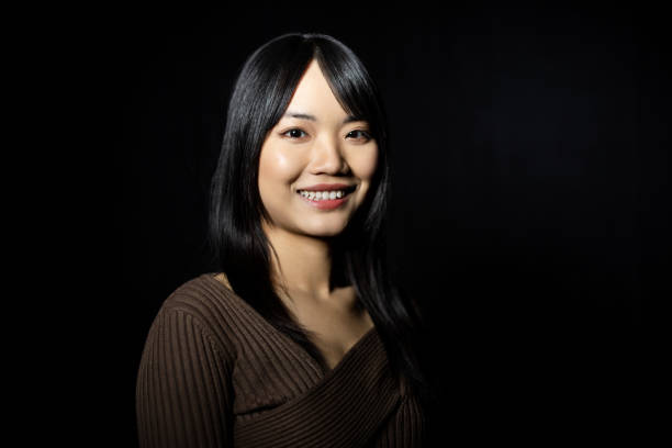 istock Smiling woman in brown sweater looking at camera on black background 2199609363