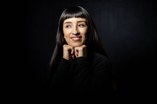 istock Hispanic woman looking away and smiling against black background 2199609369