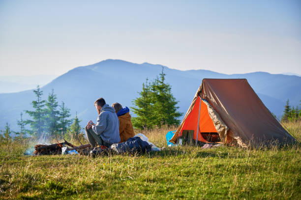 istock Two campers enjoying serene view of rolling mountains under clear sky. 2199611008