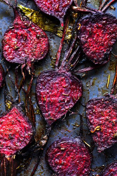 Roasted beet slices fresh from the oven. Top view of baked beetroot seasoned with spices. Close-up of beets with olive oil, salt, and pepper