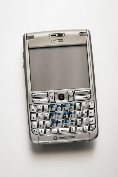 Milan, Lombardy, Italy - February 10, 2025: Retro Nokia E61 smartphone lying on a white background, showcasing its qwerty keyboard and Vodafone branding