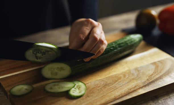 istock A woman is slicing a cucumber into rounds. 2199617035