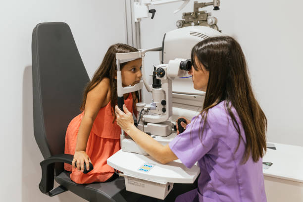 istock Optometrist performing eye exam on young girl in modern clinic 2199619315