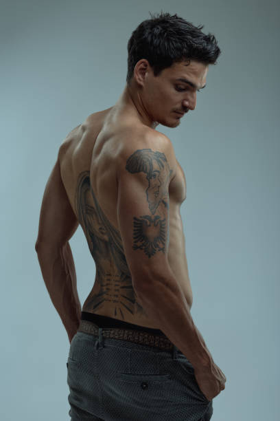 istock Young man showing his back and arm tattoos 2199619584