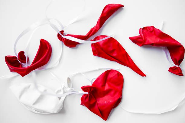 istock Deflated red and white balloons with ribbons on white background 2199619872