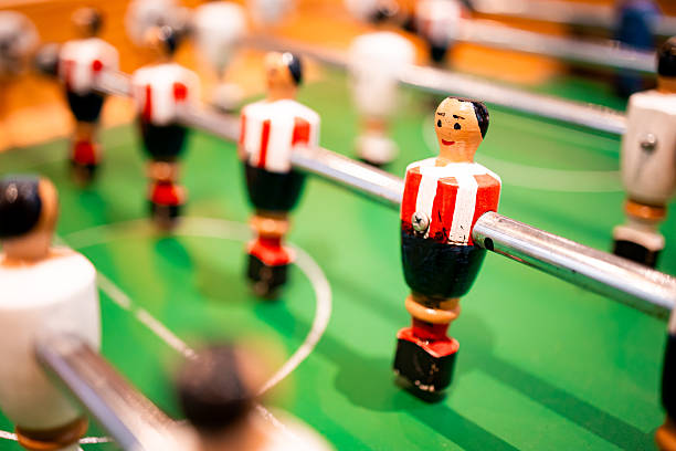 istock Foosball table close up with red and white figures on green field 2199620071