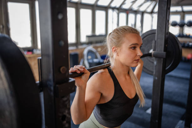 istock Focused woman performing squats with weights at a gym for strength training 2199624227