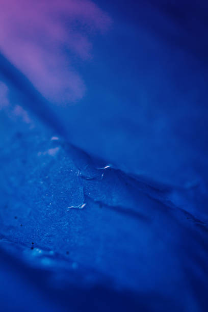 Extreme close up of blue empty plastic bag background. The plastic surface is wrinkly and tattered making abstract pattern. Selective focus, shallow depth of field.