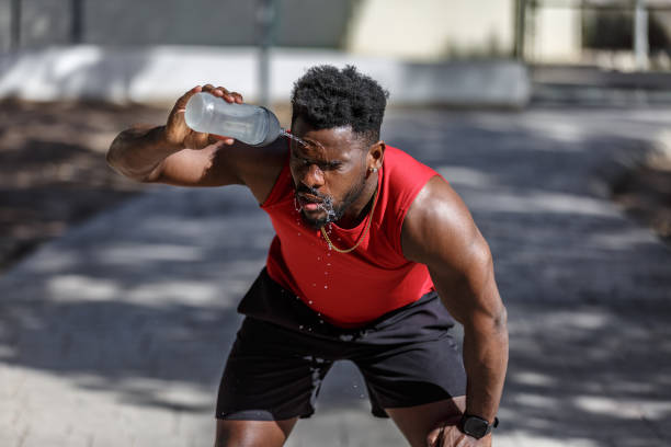 istock Man cools off with water after workout in public park during warm afternoon 2199631326
