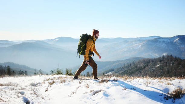 istock The man with a backpack hiking in the snowy mountains on a sunny day 2199632341