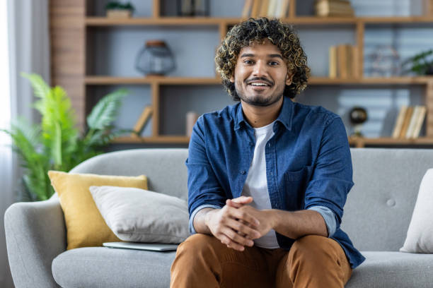 istock Smiling man sitting on a sofa in a modern home interior 2199632672