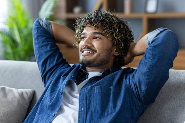 istock Relaxed man smiling while lounging comfortably on a cozy living room sofa 2199632765