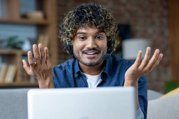 istock Man working from home remotely, sitting on sofa in living room, freelancer businessman using headset phone and laptop for video call, online meeting and remote conference 2199632775