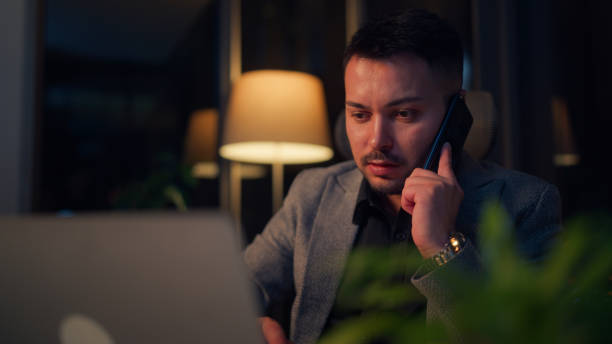istock Businessman Working Late and Talking on Mobile Smart Phone in a Modern Office 2199635277