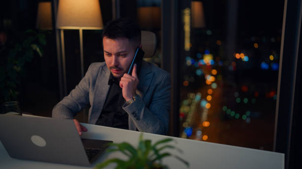 istock Businessman Working Late and Talking on Mobile Smart Phone in a Modern Office 2199635308