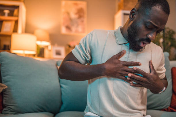 istock A black man with a painful expression is sitting on the sofa and has severe chest pains 2199636214