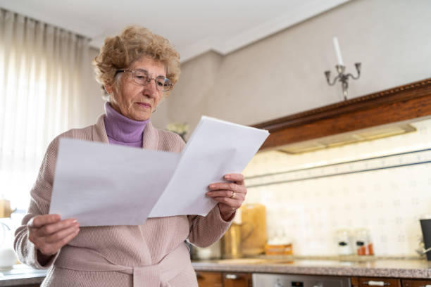 istock Thoughtful senior woman reviewing important papers in her charming kitchen space 2199636945