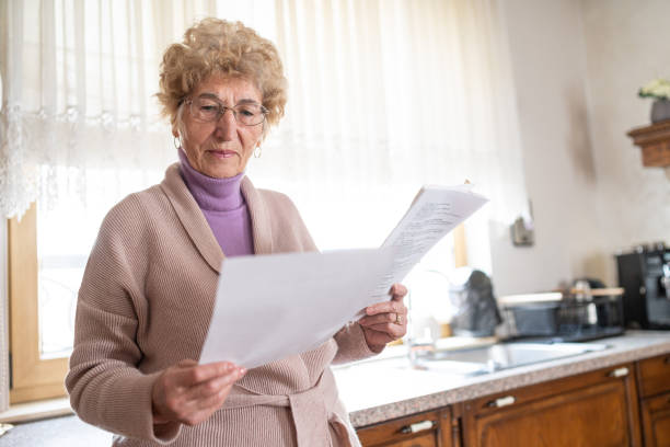 istock Thoughtful senior woman reviewing important papers in her charming kitchen space 2199636949