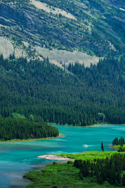 Many Glacier Hotel on Turquoise Swiftcurrent Lake - Scenic mountains with wildflowers in summer. Glacier National Park, Montana USA.