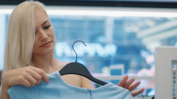 istock Young blond woman choosing clothes in a store 2199638575
