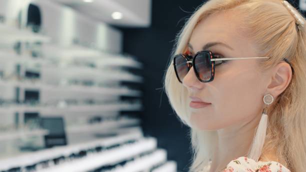 istock Elegant woman trying sunglasses in optic store 2199638621