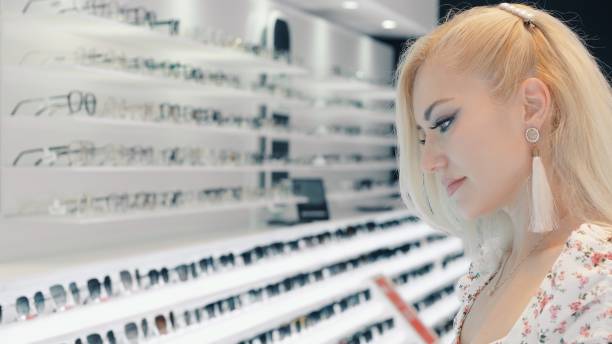 istock Customer choosing eyeglasses in optical store looking at shelves with many glasses 2199638627