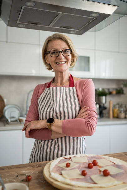 istock Middle-aged woman smiling with arms crossed and making pizza in kitchen 2199638839