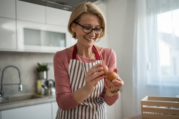 istock Middle-aged woman holding fresh eggs, smiling in modern kitchen 2199638911