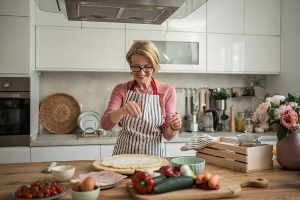 istock Mature woman making homemade pizza in the kitchen 2199638913