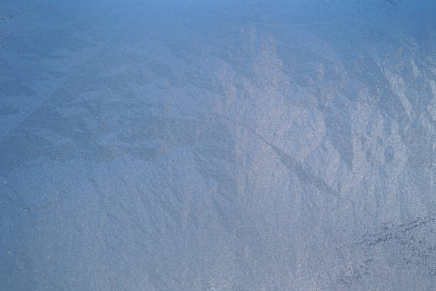Blue and purple coloured frozen condensation on single pane window glass