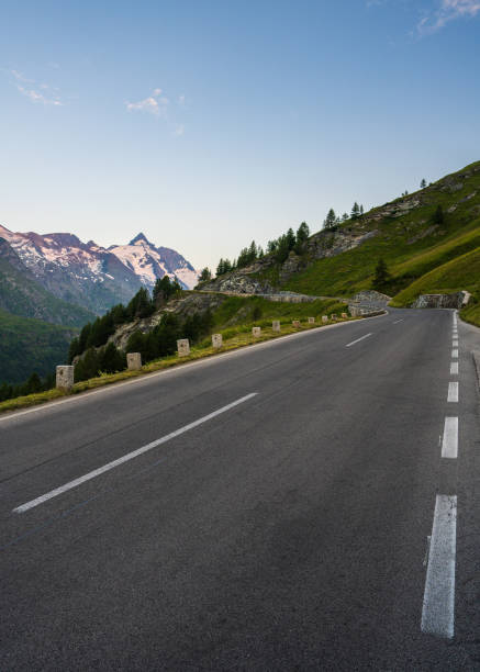 istock Asphalt road winds among alpine meadows, cliffs, leading to majestic Grossglockner mountain. Snow capped peaks on horizon. For themes of travel, nature, outdoor activities. 2199651885