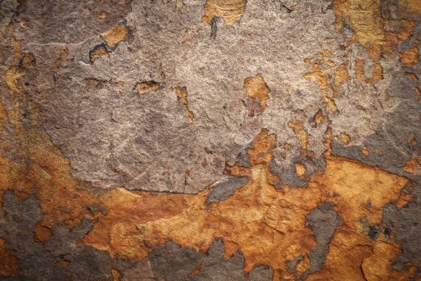 Brown grey rough stone wall with peeling of layer stone surface rusted cracks for abstract background and texture, interior or exterior design. Beautiful patterns, space for work, banner, close up.