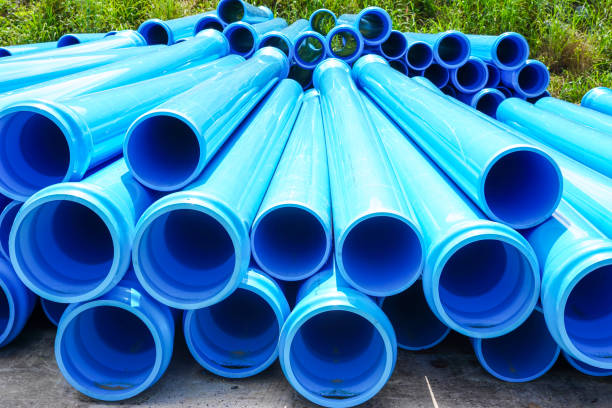 Stack of large blue water pipes, PVC nylon water pipes unpacked used on the construction site for installation, water supply repair or plumbing drain infrastructure earthworks.