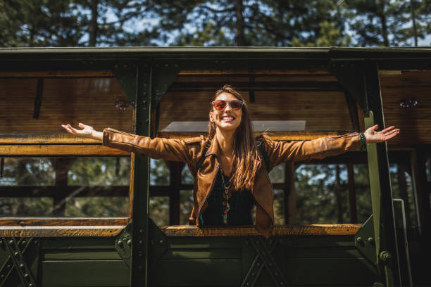 A smiling young woman looking and greeting through a window while traveling by a retro train.