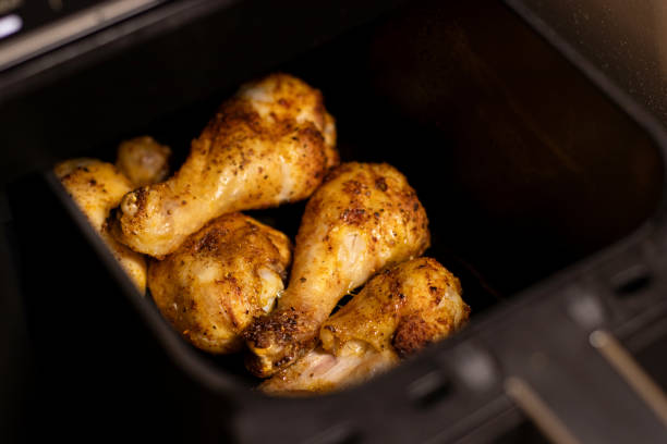 istock Close up an open black air fryer with roasted chicken drumsticks inside 2199666573