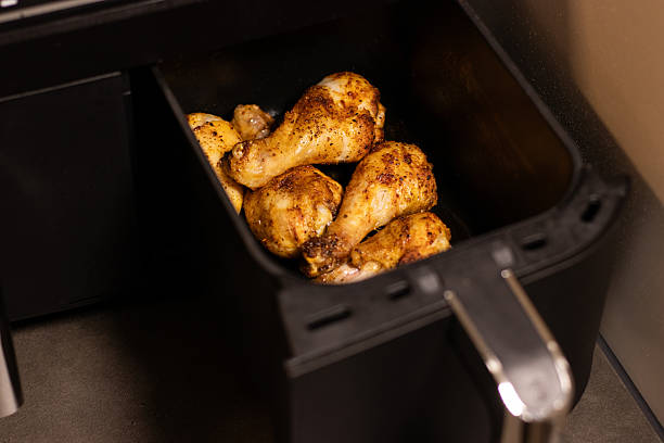 istock Close up an open black air fryer with roasted chicken drumsticks inside 2199666596