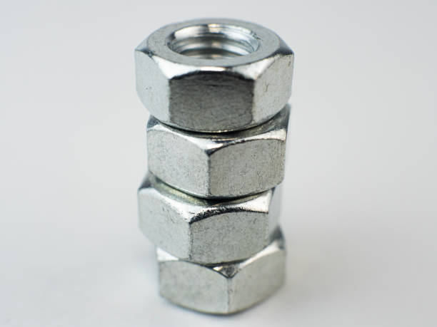 istock Metal nuts close up stacked together on a plain backdrop. shallow depth of field 2199669180