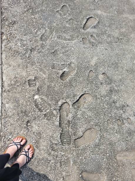 istock A person is standing on a sidewalk which has footprints on it 2199669659