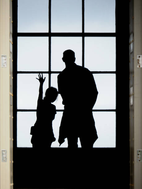 Heartwarming silhouette of a family joyfully waving from a brightly lit window, embodying connection and anticipation, while radiating love and togetherness in a cheerful home setting