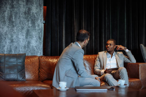 istock Businessmen talking on a leather couch in a modern hotel lobby 2199672554