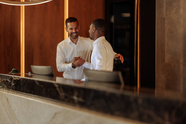 istock Hotel receptionist shaking hands with businessman at reception desk 2199672573