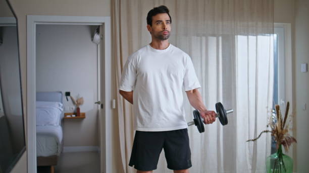 istock Strong man lifting dumbbell at strength training home. Determined sportsman 2199672664