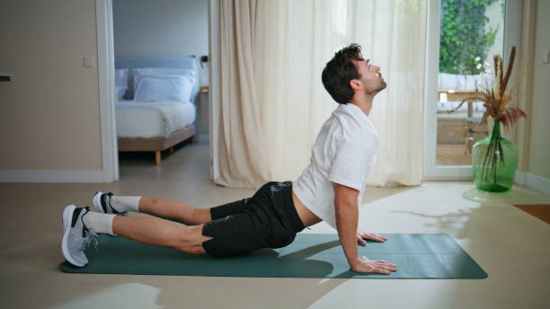 istock Handsome athlete stretching body practicing upward dog yoga pose on mat. 2199674229