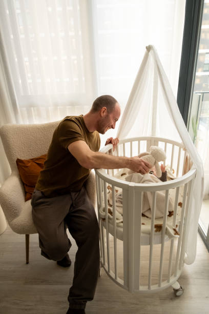 istock Man playing with his child in the crib 2199675558