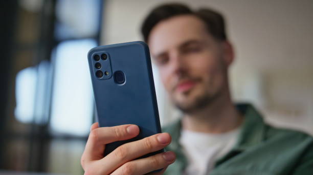 istock Blurred guy looking mobile phone receiving message notification at home closeup 2199680401