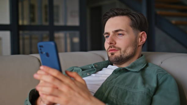 istock Resting man texting smartphone lying on home couch closeup. Guy typing sms alone 2199685143